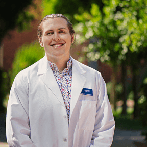 Male student in white coat, smiling