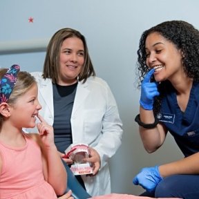 Child pointing to teeth with dentist