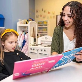 Child learning to read a picture book with help from a speech language specialist