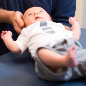 Doctor holding baby's head during checkup.