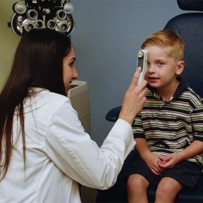 Jackson gets his eye checked by a doctor in a white coat at the Eye Institute.