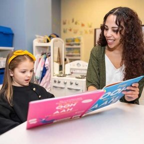 Child reading to Speech-language pathologist. 