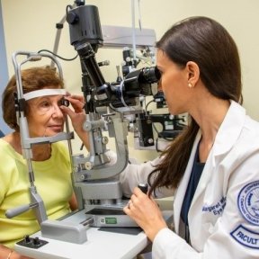 Optometrist performs eye exam on a woman.