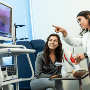 Speech-language pathologist uses model and imaging equipment while meeting with a patient.