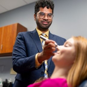 Optometrist examines patient eyes.
