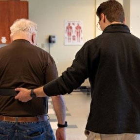 Physical therapist helps patient walk.