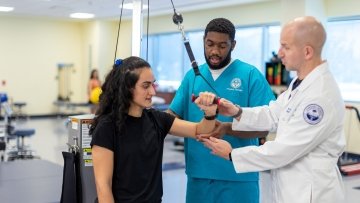 Physical therapy student and faculty help patient with arm exercises.