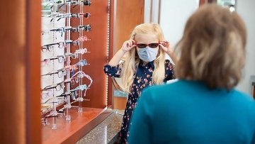 Young girl tries on sunglasses.