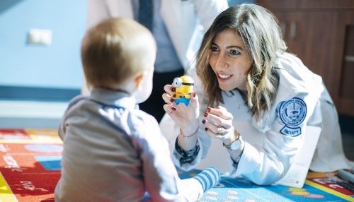 Doctor using soft toy to help with toddler eye exam.