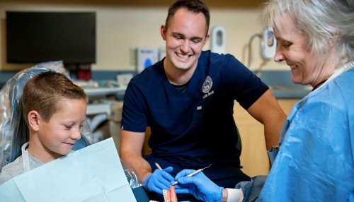 child with dentist looking at a teeth mold