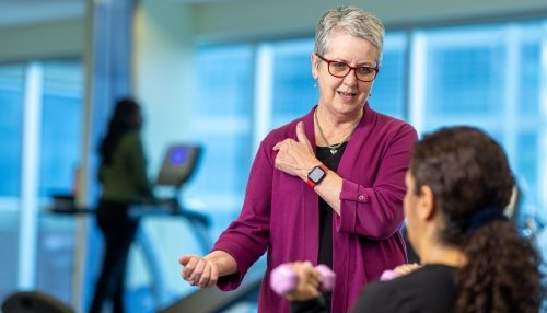 Doctor demonstrates shoulder exercises to woman.