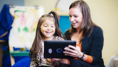 Smiling young girl works with a speech-language pathologist.