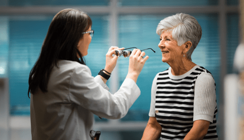 Optometrist holds a pair of glasses while talking to a patient.