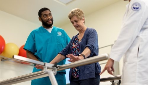 Elderly patient practicing balancing herself with help from physical therapists