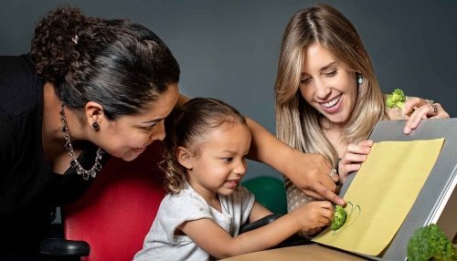 Child, alongside two speech language pathologists, pointing to picture