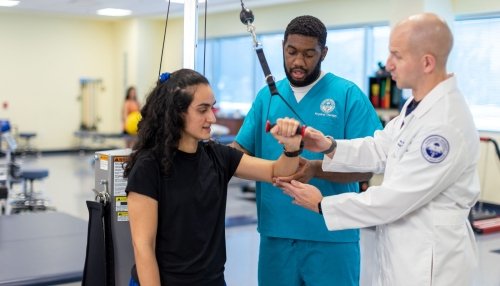 Physical therapy student and faculty help patient with arm exercises.