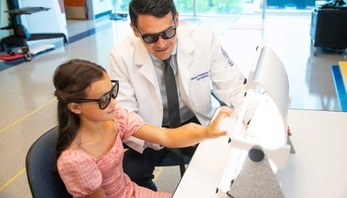 Young girl uses spectogram while working with an optometrist.