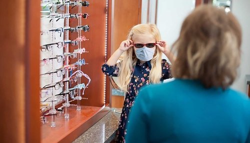 Young girl tries on sunglasses.