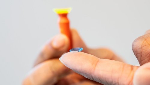 Hand with specialty contact lens on pad of finger.