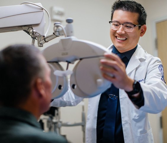 Eye specialist uses optical equipment to examine patient's eyes.