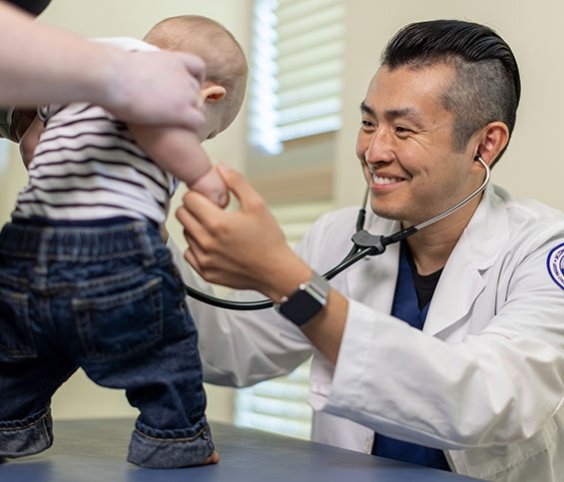 Doctor helps baby stand up to check heartbeat