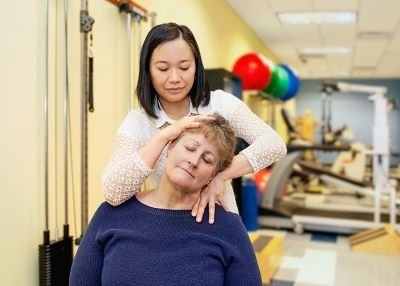 Physical therapist gently manipulates a patient's neck.