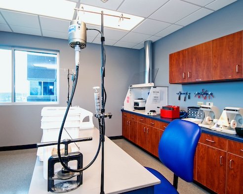 A contact lens lab room equipped with specialized fitting instruments, woodgrain cabinetry, and optical tools on the countertop.